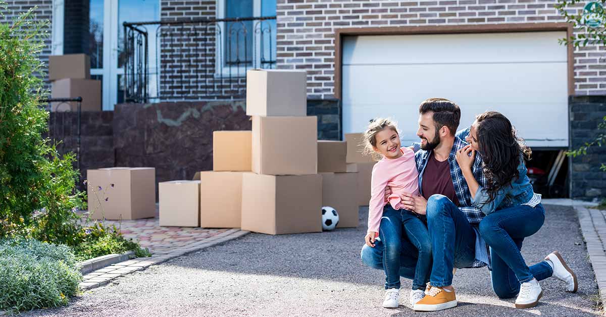 Familie mit Unzugskartons vor neuem Haus auf dem Land