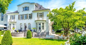 Eine Villa am Rande der Stadt im sommerlichen Sonnenschein, umgeben vom Grün der Bäume. Herrschaftlich!
