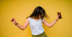 Junge Frau tanzt ausgelassen vor gelber Wand – Symbolbild für Lebensfreude, Freiheit und positive Emotionen | Notartermin